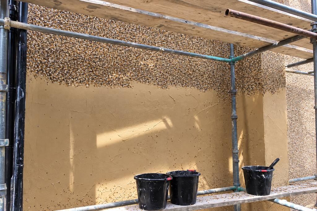 Decorative aggregate being applied during a dry dash rendering project by P3 Plastering