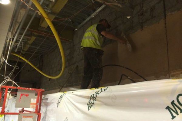 P3 plasterer applying solid plaster to a masonry wall