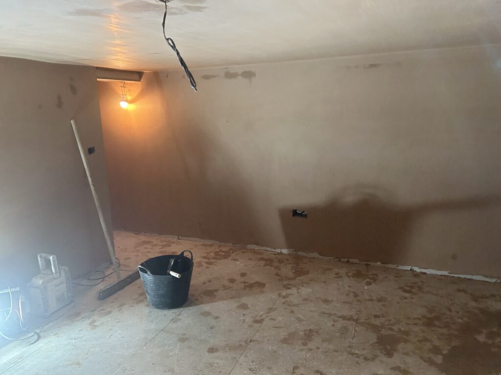 Freshly plastered basement walls showing the smooth finish around a doorway and across the main wall.